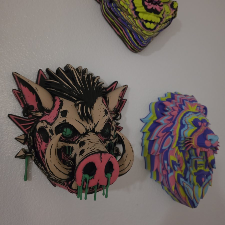 Layered multicolor 3D printed animal-head wall art — a punk boar, a rainbow lion and a neon cat