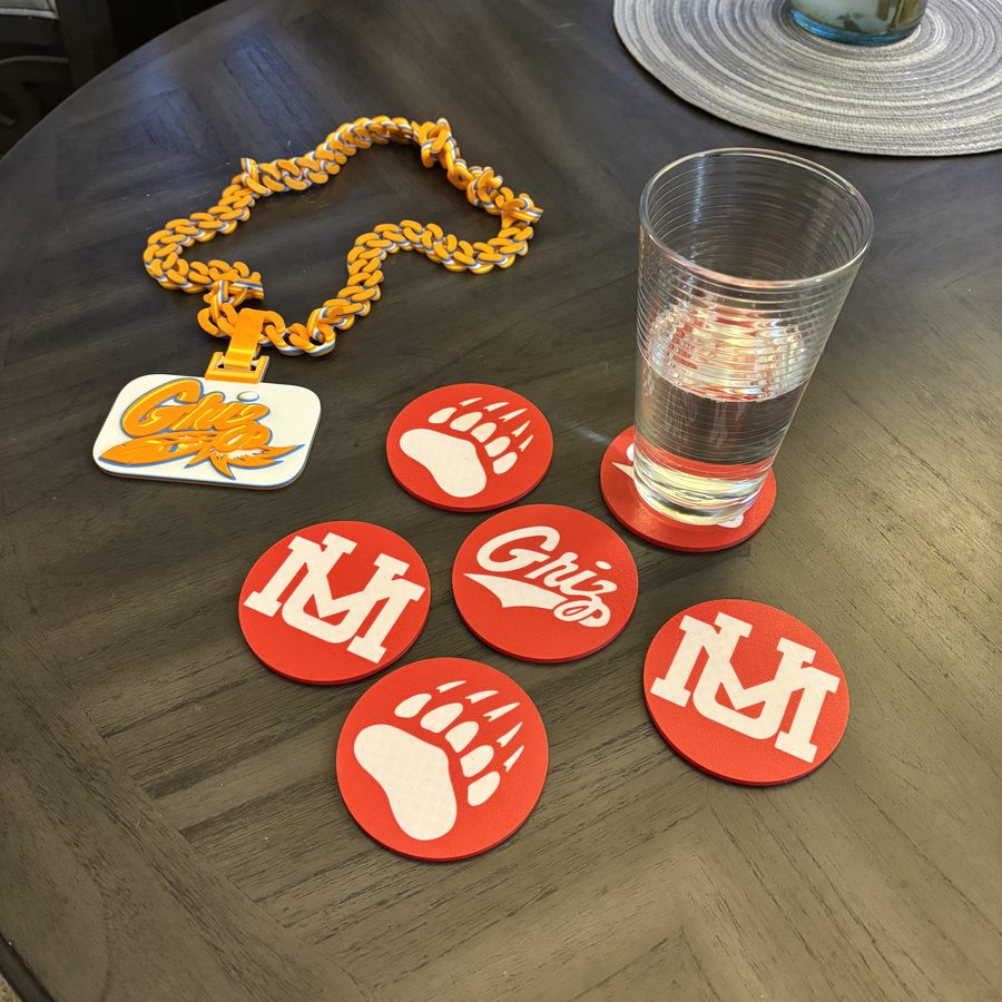 3D printed Montana Grizzlies fan chain with Griz pendant and a set of six red and white logo coasters